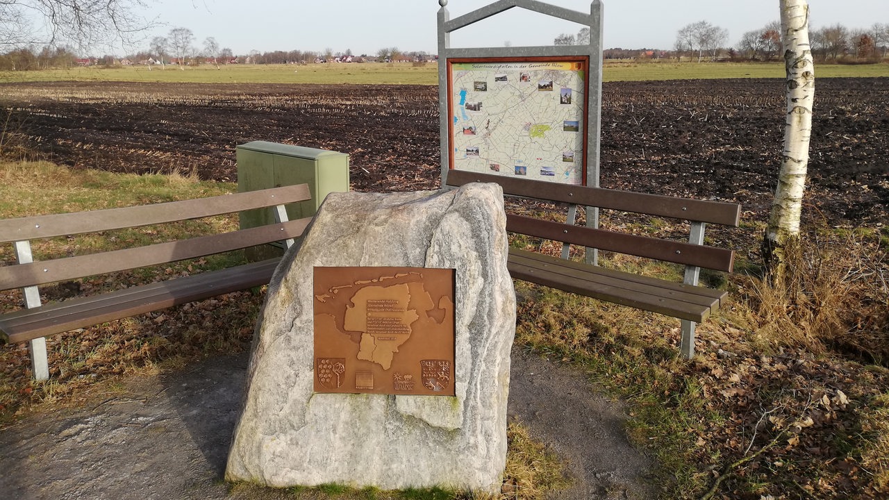 ein Findling mit einer Schrifttafel, daruf der Umriss von Ostfriesland