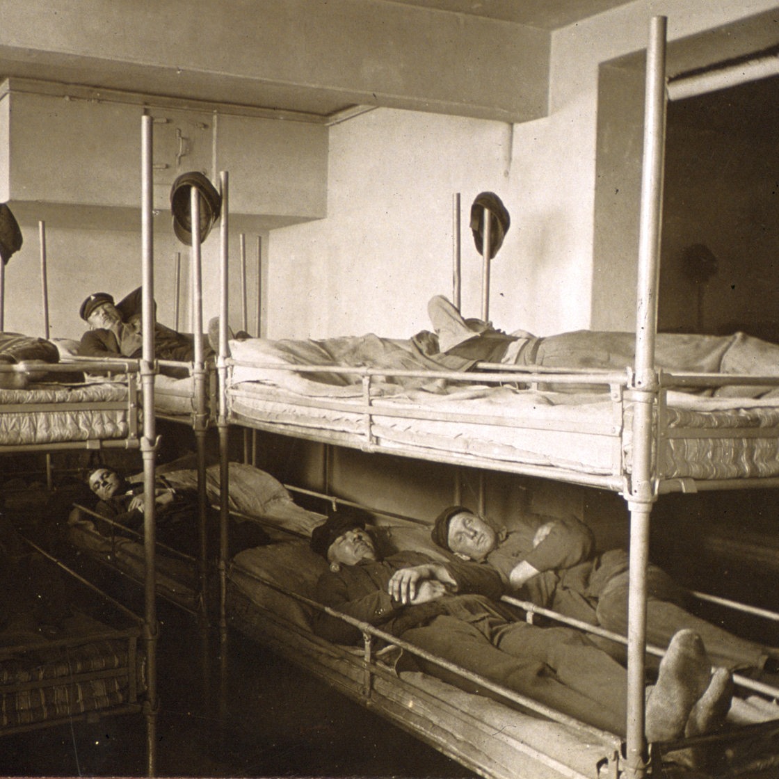 Arbeiter liegen auf Stockbetten (historische Aufnahme)