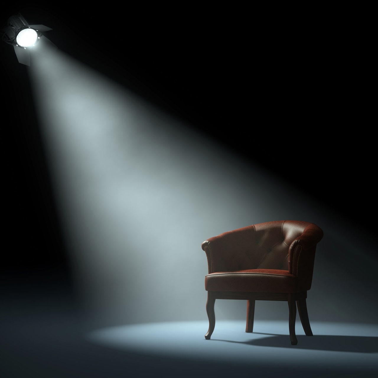 Ein Sessel auf einer Bühne, angestrahlt von einem Scheinwerfer