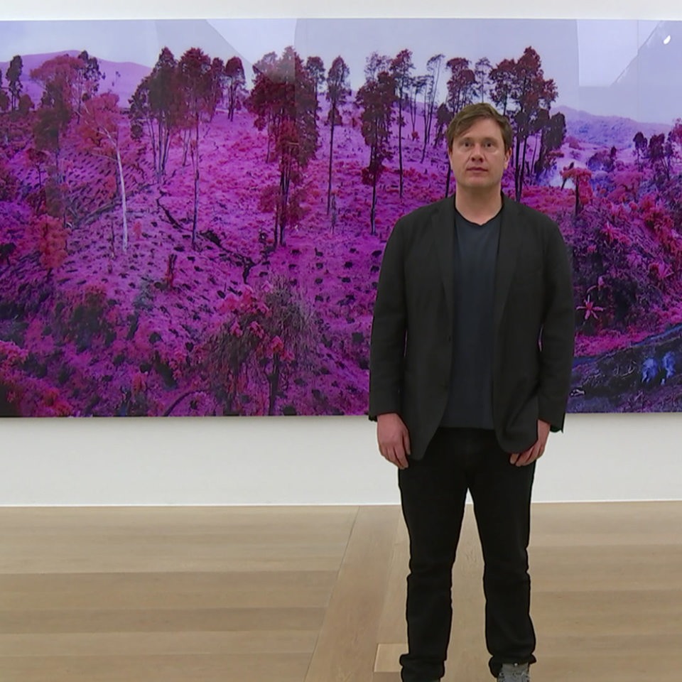 Richard Mosse auf einer Ausstellung vor einem seiner Bilder.