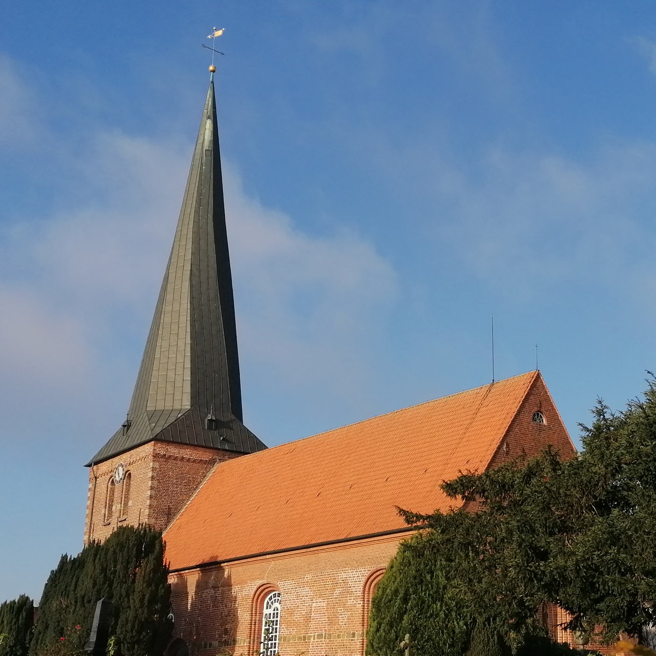 eine Kirche mit gedrehtem Kirchturm vor blauem Himmel