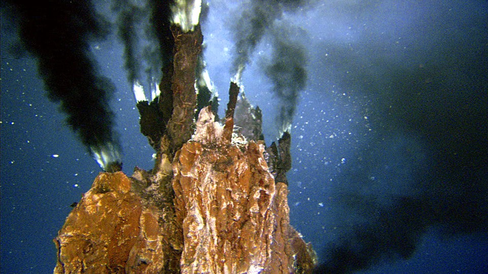 Eine Unterwasseraufnahme zeigt Gestein, aus dem schwarzer Rauch aufsteigt