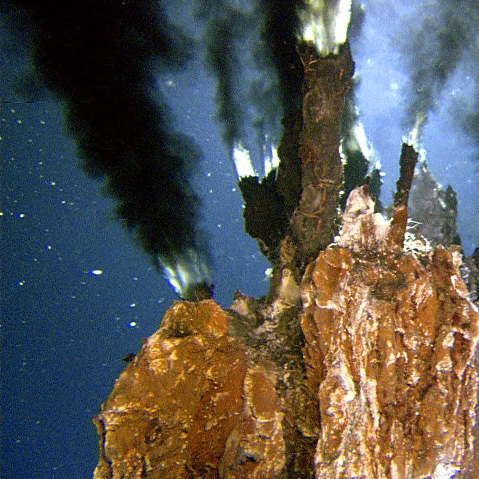 Eine Unterwasseraufnahme zeigt Gestein, aus dem schwarzer Rauch aufsteigt