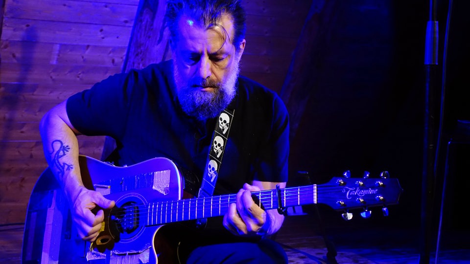 Sean Rowe steht mit seiner Gitarre auf der Bühne