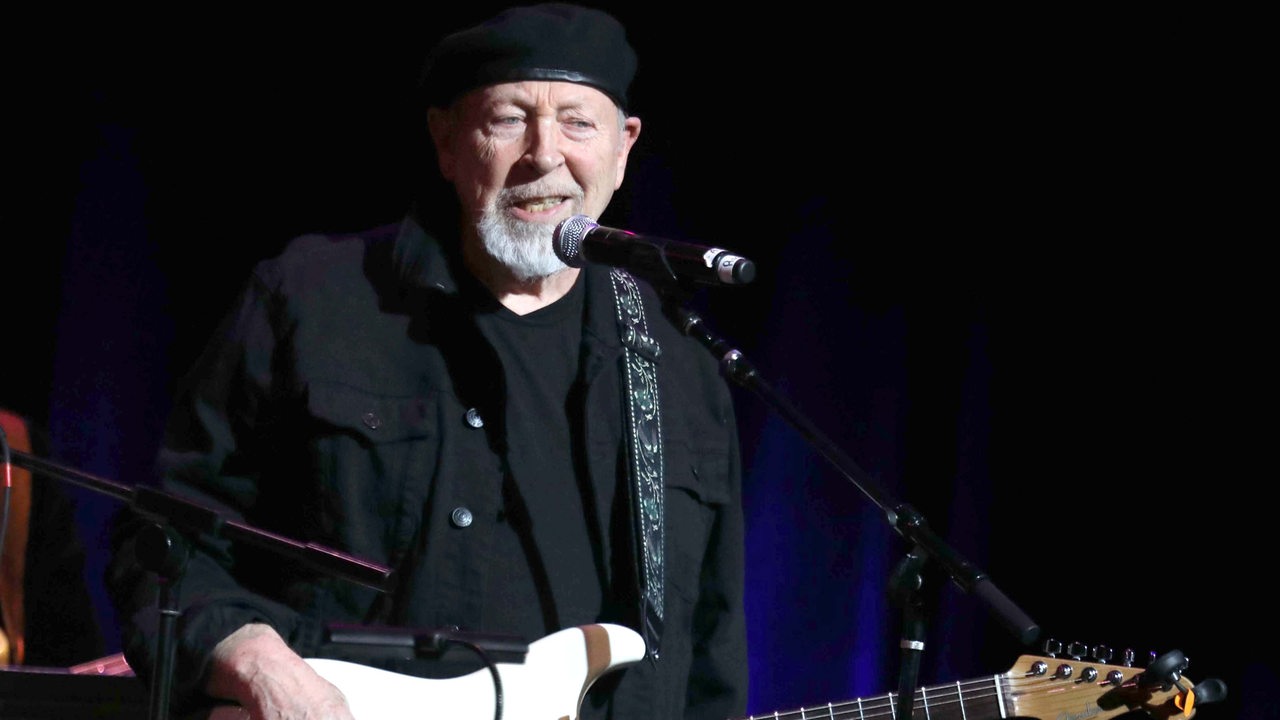 Richard Thompson mit Gitarre singt ins Mikrofon.