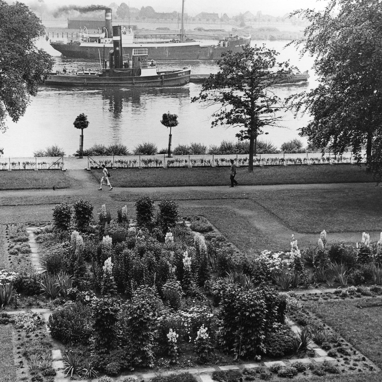 ein Park, im HIntergrund die Weser mit Schiffen; historische Schwarzweiß-Aufnahme