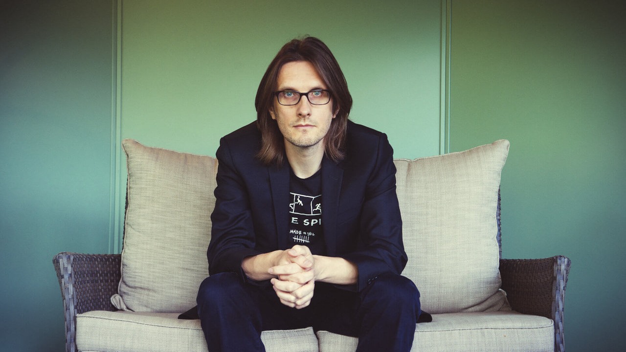 Der Musiker Steven Wilson sitzt auf einer Couch in schaut in die Kamera