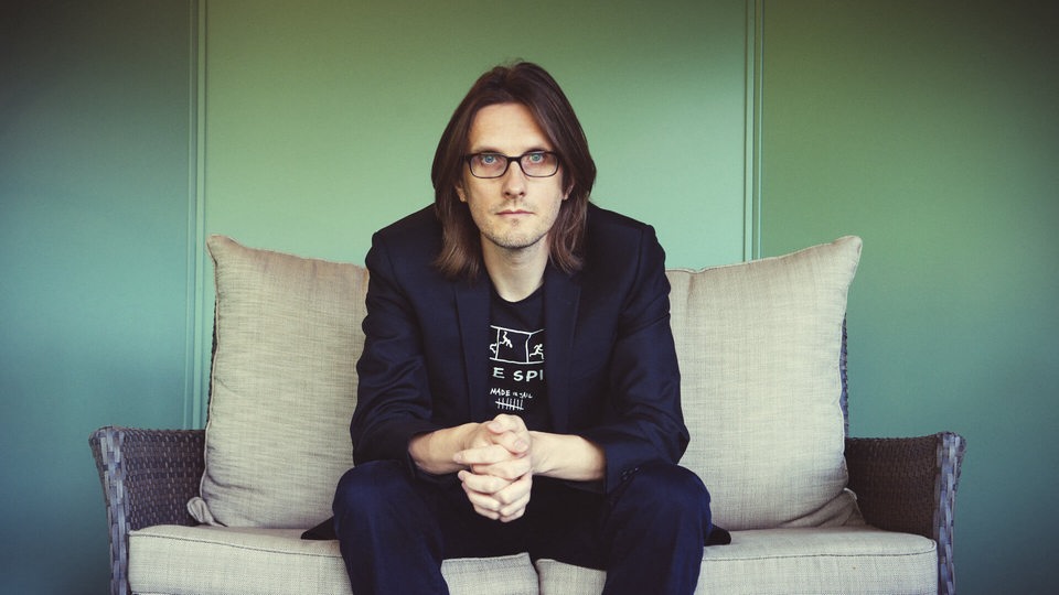 Der Musiker Steven Wilson sitzt auf einer Couch in schaut in die Kamera