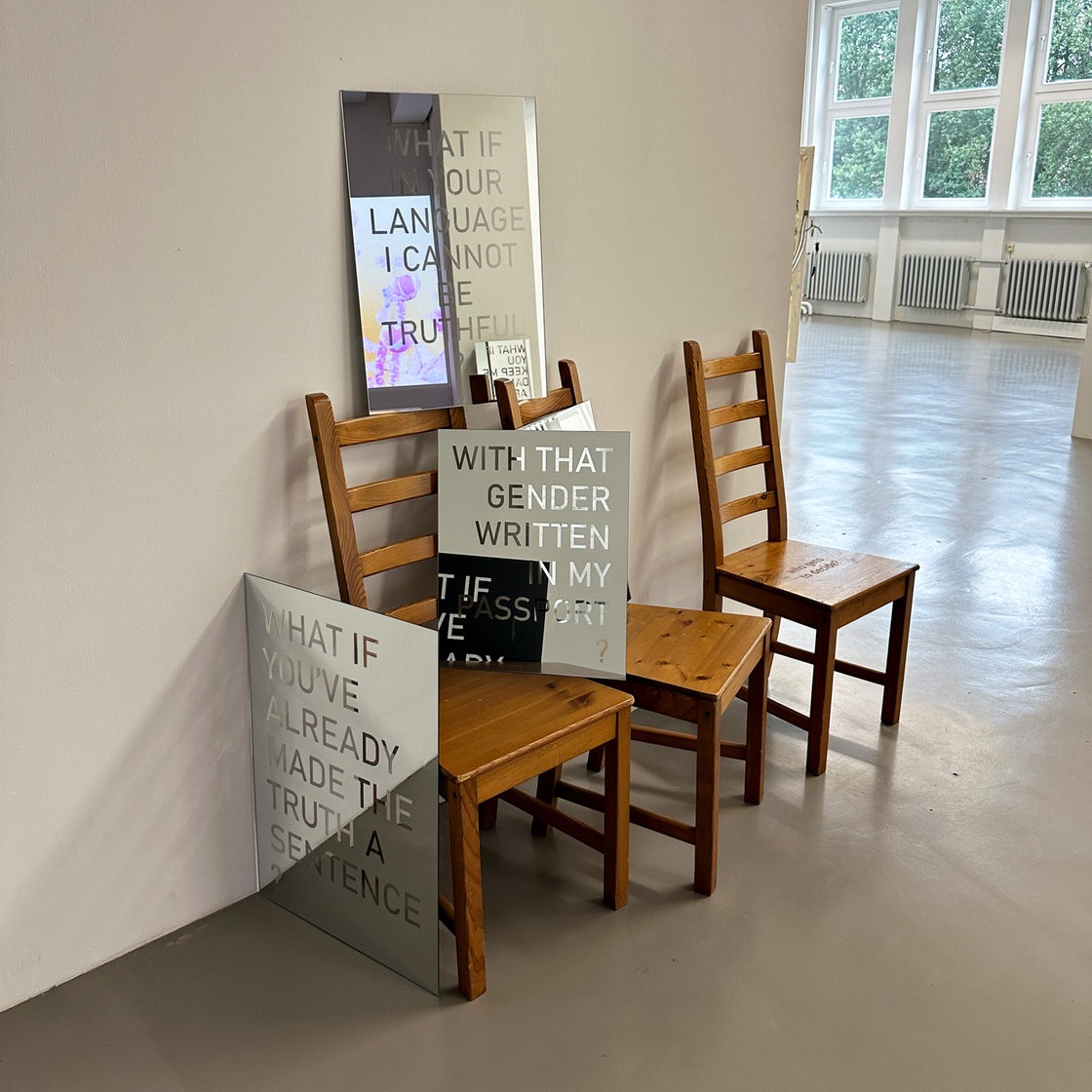 3 Stühle mit verschiedenen Plakaten stehen an einer Wand