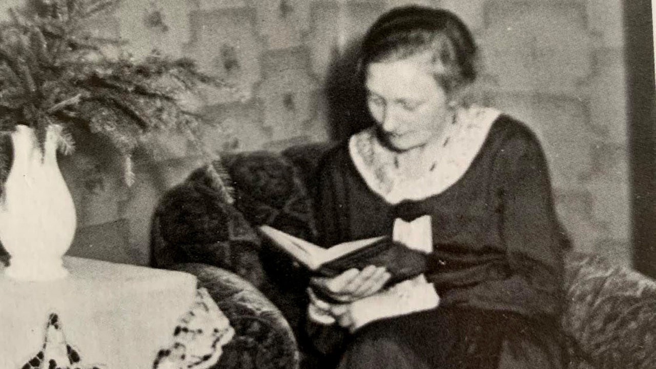 Schwarzweiß-Bild: Eikne Frau sitzt in einem Sessel und liest