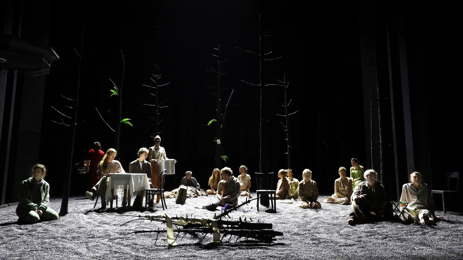 Szene aus "Erbarmen": Menschen sitzen auf einer Bühne im Licht
