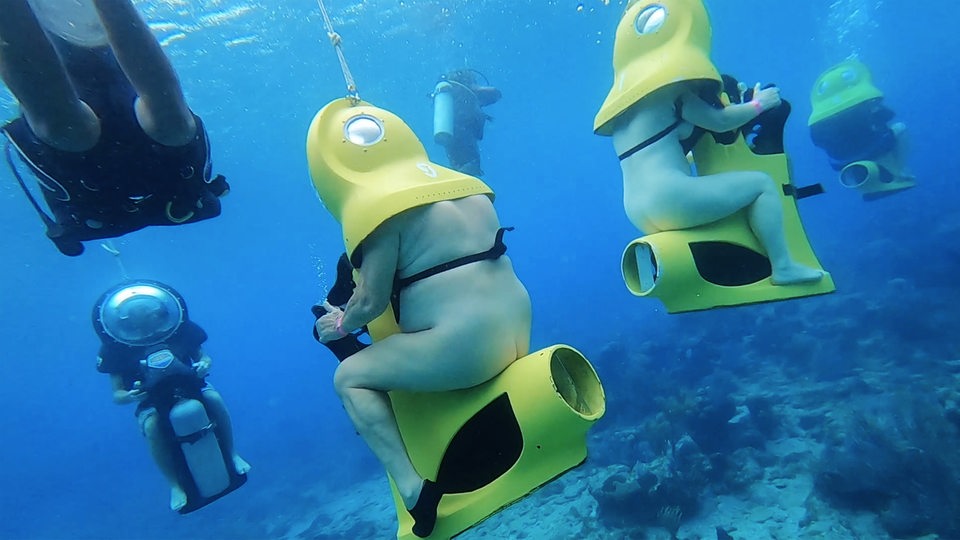 Zwei nackte Menschen unter Wasser auf einer Unterwasser-Scooter