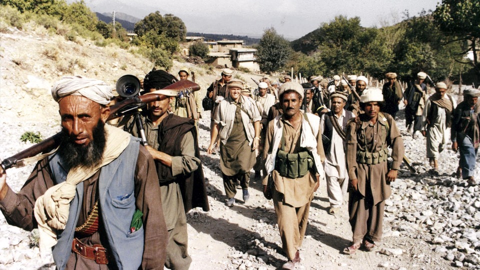 Eine Gruppe von afghanischen Kämpfern. Eine blonde Frau in Männerkleidern ist unter ihnen.