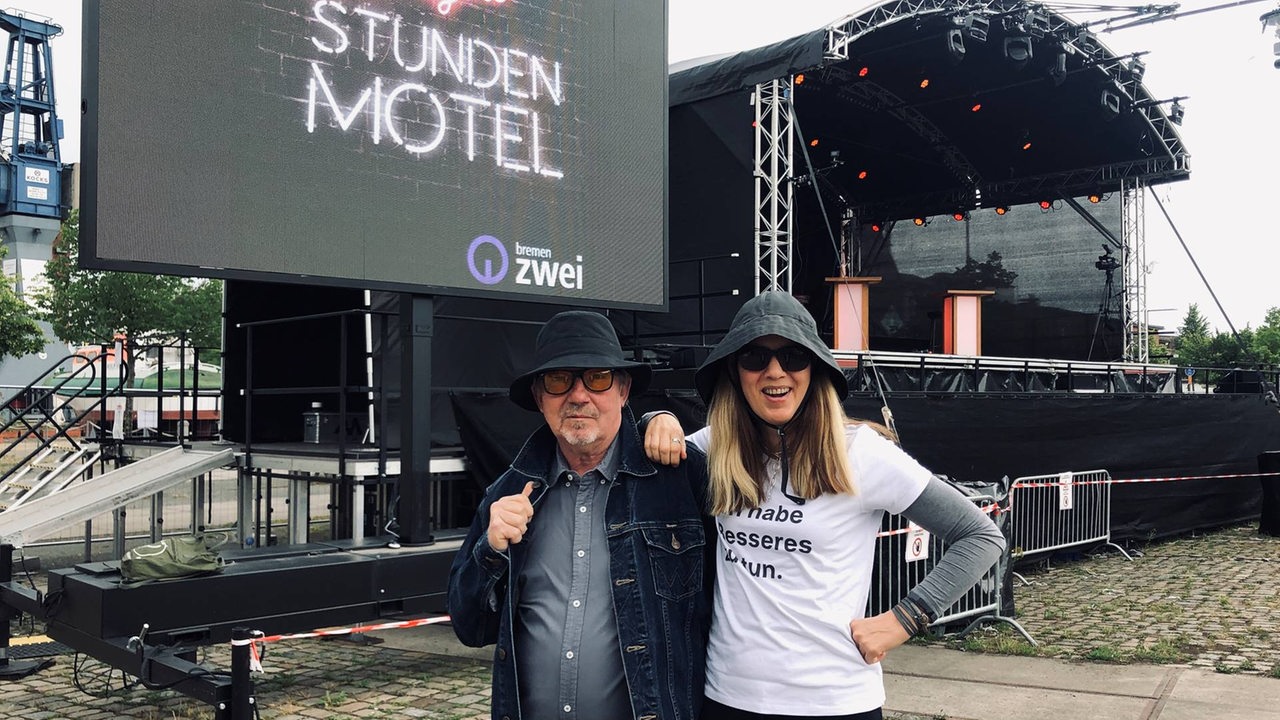 Dietmar Wischmeyer und Tina Voß mit Hüten und Sonnenbrillen vor einer Bühne