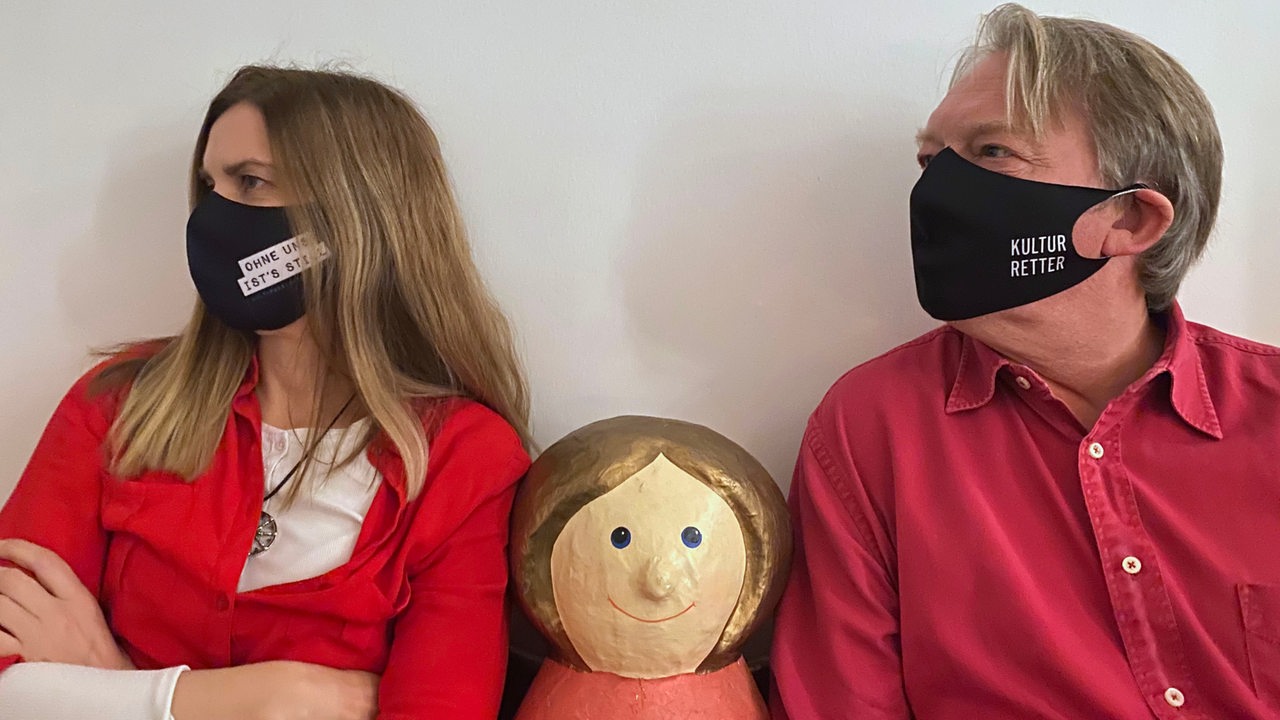 Dietmar Wischmeyer und Tina Voß mit Pappmachéfigur und Mund-Nasen-Schutz