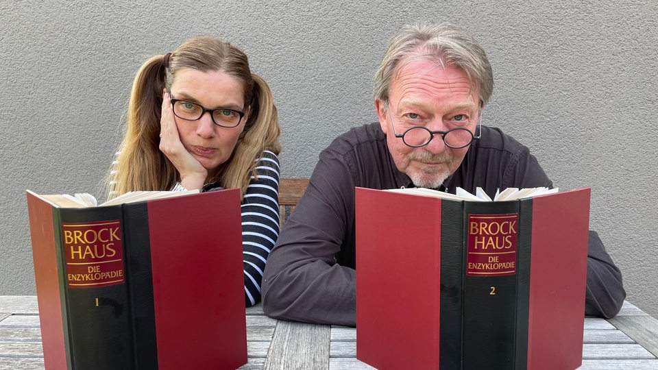 Dietmar Wischmeyer und Tina Voß sitzen mit Büchern am Tisch