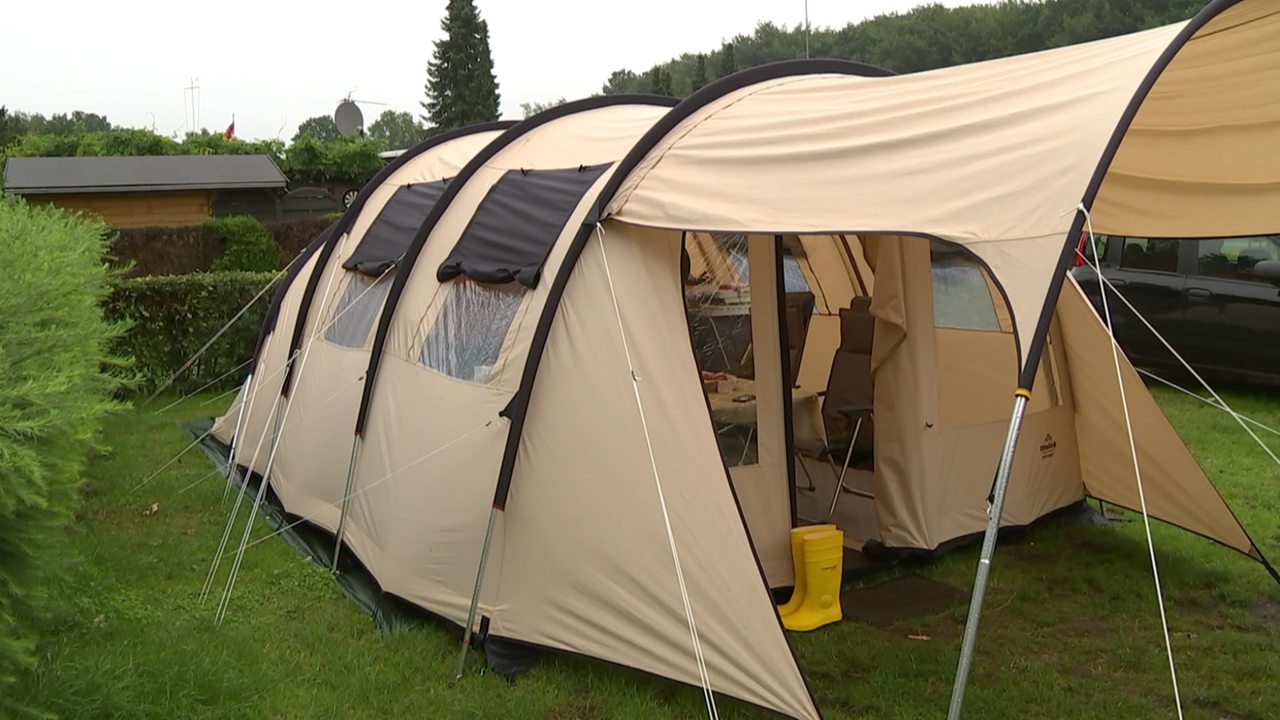 Ein großes beiges Zelt auf einem Campingplatz.