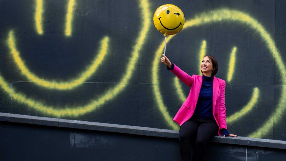 Eine Frau hält einen Smiley-Ballon in der Hand