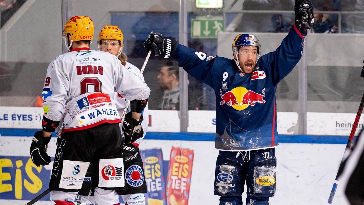 Münchens Eishockey-Profi Ben Street bejubelt einen Treffer, neben ihm zwei enttäuschte Spieler der Fischtown Pinguins.